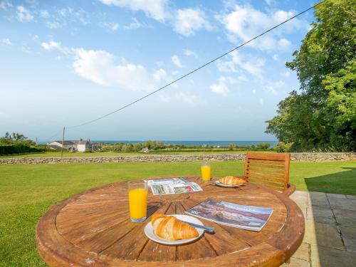 a wooden table with bread and orange juice on it at Bryn Awelon - Uk44122 in Moelfre