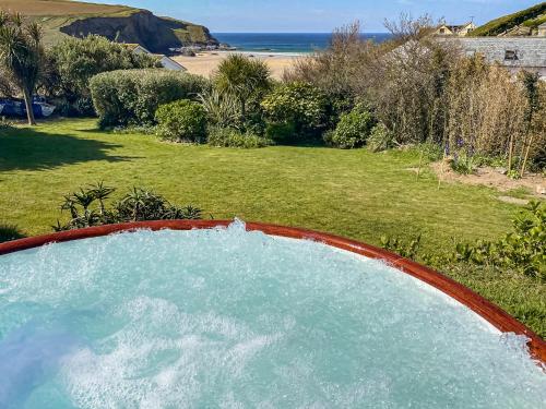 a hot tub in a yard with a view of the beach at Blue Seas in Mawgan Porth
