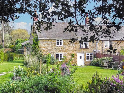 ein Backsteinhaus mit Garten davor in der Unterkunft Barters Cottage in Chideock