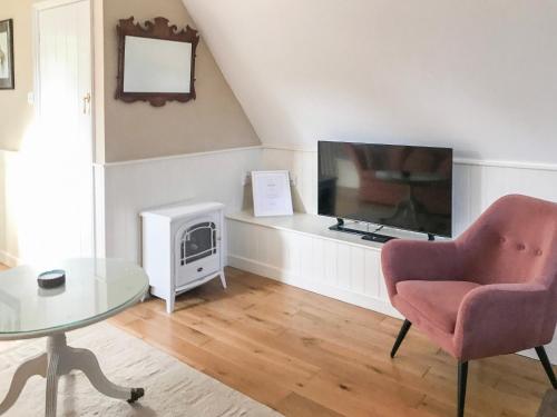 a living room with a tv and a chair and a table at Goodwood Coach House in Westhampnett