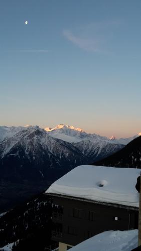 a snow covered mountain range with a building in the foreground at Tamara Parterre in Riederalp
