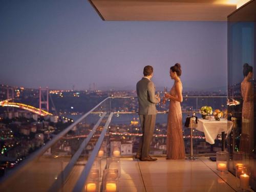 a bride and groom standing on the top of a building at Raffles Istanbul in Istanbul