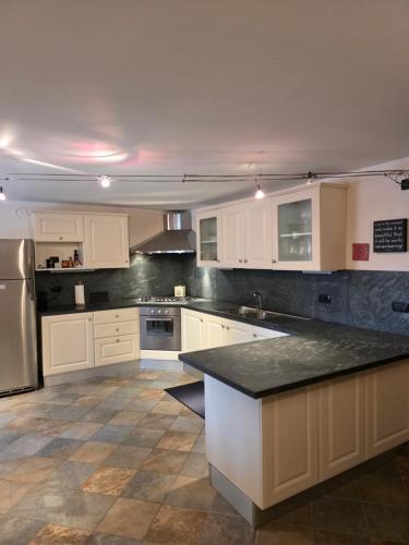 Una cocina con gabinetes blancos y una encimera negra. en Langhe Bee Home, en Cravanzana
