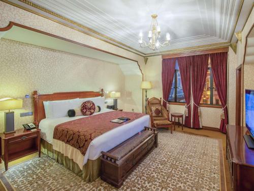 a hotel room with a bed and a chandelier at Fairmont Peace Hotel on the Bund in Shanghai