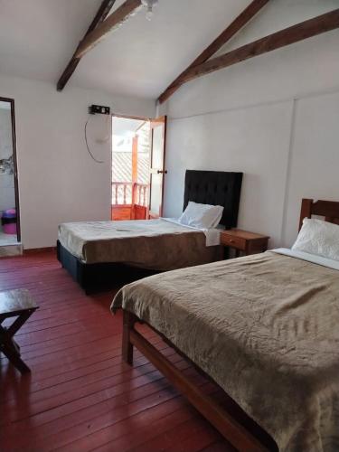a bedroom with two beds and a window at Hospedaje Apu San Isidro in Urubamba
