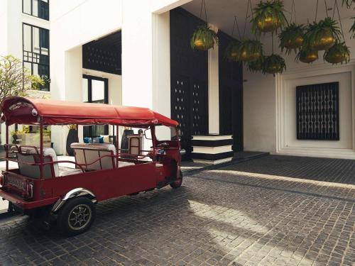 a red golf cart parked in front of a building at Mövenpick Hotel Sukhumvit 15 Bangkok in Bangkok