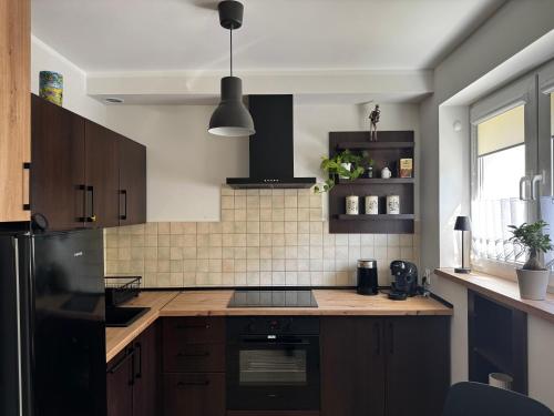 a kitchen with wooden cabinets and a black refrigerator at Apartament Muzyczny Kącik przy Rynku in Świdnica