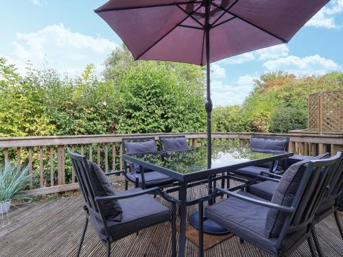 una mesa y sillas con una sombrilla en la cubierta en Riverview, en Somerford Keynes