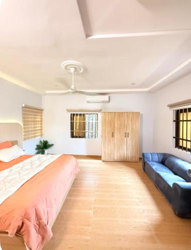 a bedroom with a large bed and a blue couch at trois chambres et salon avec balcon à Porto Novo in Porto-Novo