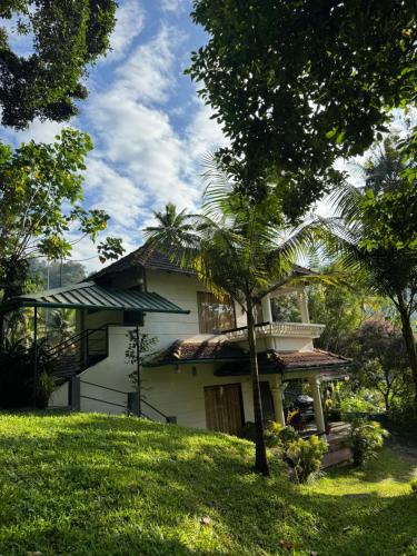 a white house with a tree in front of it at Thoppil Homestay Munnar in Munnar