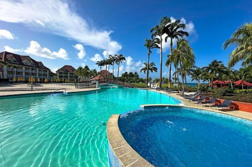 uma grande piscina com cadeiras e palmeiras em Suite Paradis Village Vacances Vue mer & piscine em Sainte-Luce