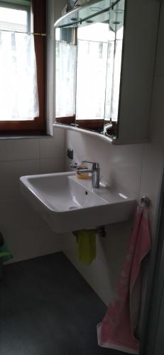 lavabo blanco en un baño con 2 ventanas en Ferienwohnung Eichfeld, en Malsfeld