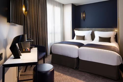 パリにあるホテル ル 10 BISの大きなベッドとデスクが備わるホテルルームです。