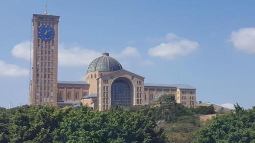 un bâtiment avec une tour d'horloge en face d'un bâtiment avec une tour d'horloge dans l'établissement Hotel Pousada do Papa, à Aparecida