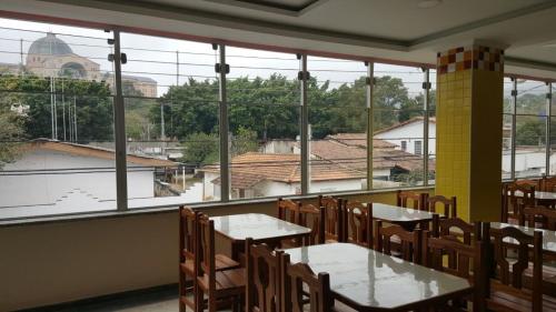 a dining room with tables and chairs and large windows at Hotel Pousada do Papa in Aparecida