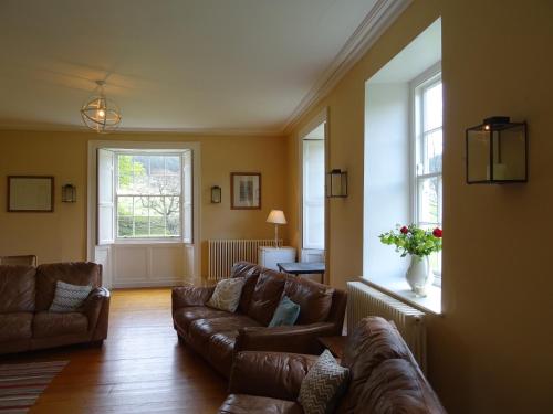 a living room with brown leather couches and a window at Baysdale Abbey in Battersby