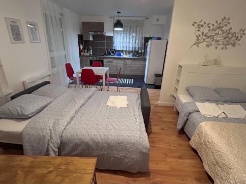 a bedroom with two beds and a table and a kitchen at Charmant Studio proche tramway in Strasbourg