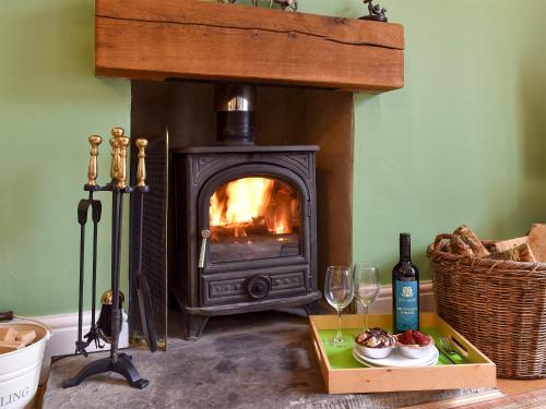 a living room with a fireplace with food and wine glasses at Coach House Cottage in Buckden