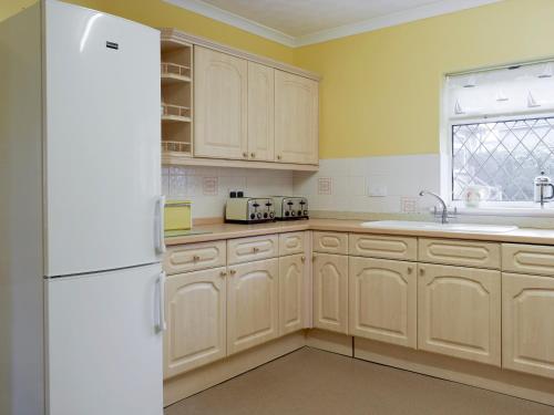 a kitchen with wooden cabinets and a white refrigerator at Green Acre Cottage in Kilgetty