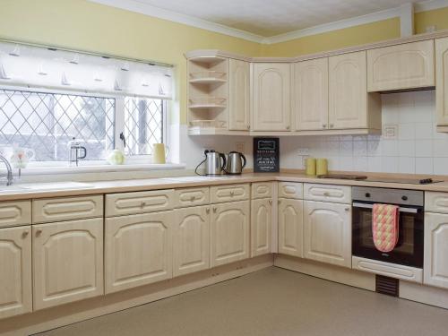 a kitchen with white cabinets and a sink and a window at Green Acre Cottage in Kilgetty