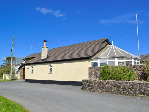 a house with a stone wall next to a street at Green Acre Cottage in Kilgetty