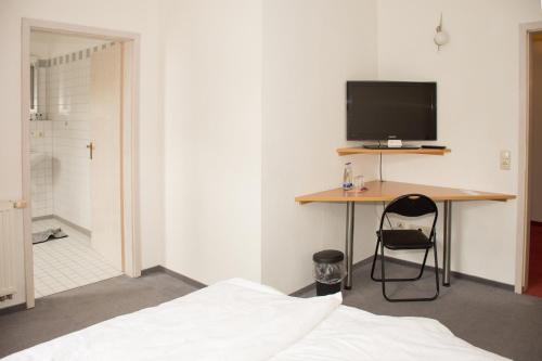 a bedroom with a bed and a desk with a television at Dorfschänke Kreuz in Landensberg