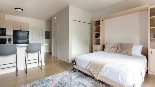 a bedroom with a white bed and a kitchen at Landing Apartments - Woodburn in Woodburn