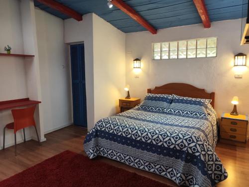 a bedroom with a bed and two lamps and a desk at Hostal El Carmen de Pirque in Pirque