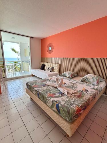 a bedroom with a large bed and an orange wall at Suite Sabi Vue Mer in Le Diamant
