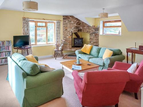 a living room with couches and chairs and a tv at Erw Goed Old Barn in Arthog