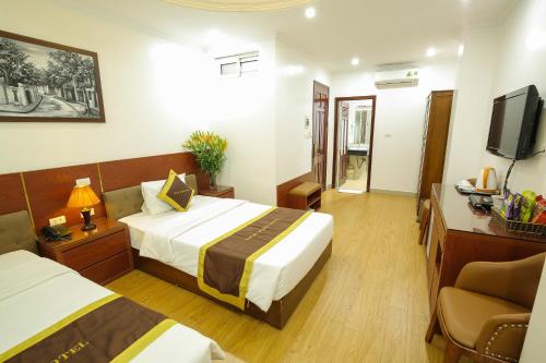 a hotel room with two beds and a television at Bạch Dương Hotel Hà Nội in Hanoi