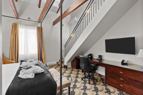 a room with a bed and a desk and a tv at Hotel Manoir D'Auteuil - Par Aneyro in Quebec City
