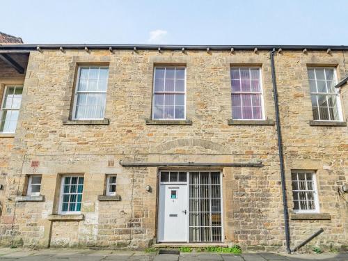 een oud bakstenen gebouw met een witte deur bij Shire Cottage - Uk37451 in Pateley Bridge