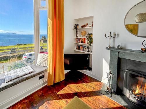 a living room with a fireplace and a view of the ocean at Aird Cottage in Dunure
