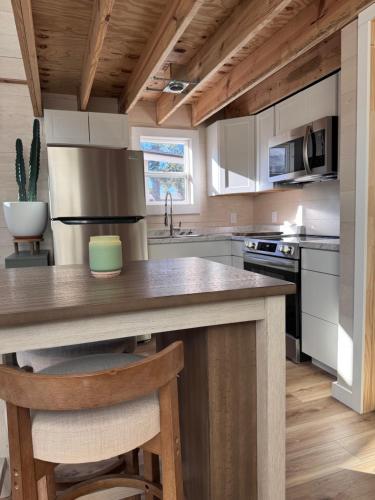 サンアントニオにあるModern Tiny Barn Urban Oasis in San Antonioの白いキャビネット付きのキッチン、カウンター(スツール付)