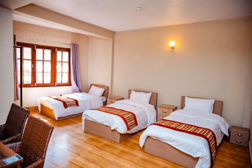 a hotel room with two beds and a chair at Tashi Pal Hotel Pvt. Ltd in Kathmandu