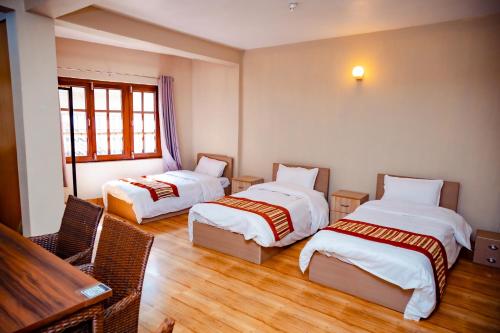 a hotel room with two beds and a table at Tashi Pal Hotel Pvt. Ltd in Kathmandu