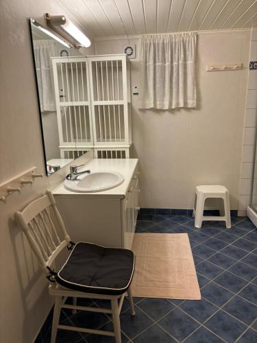 a bathroom with a sink and a mirror and a chair at Strand huset in Hitra