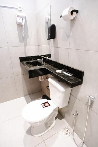 a bathroom with a toilet and a phone on the wall at Pousada Malibu 116 in Vitória da Conquista