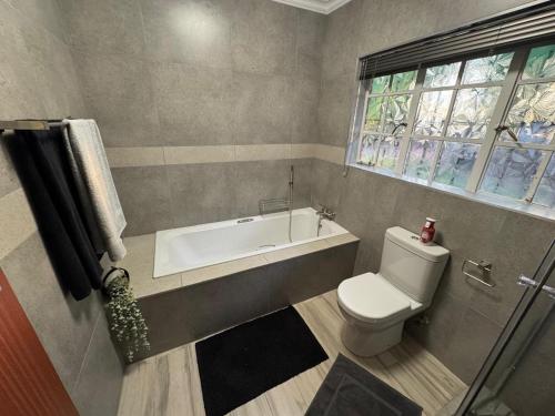 a bathroom with a tub and a toilet and a sink at ORT Tranquil Stay in Boksburg