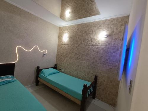 a small bedroom with a bed with a blue light at Edícula aconchegante em Peruíbe in Peruíbe