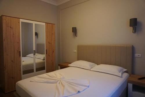 a bedroom with a white bed and a mirror at Bujorul Oltului in Călimăneşti