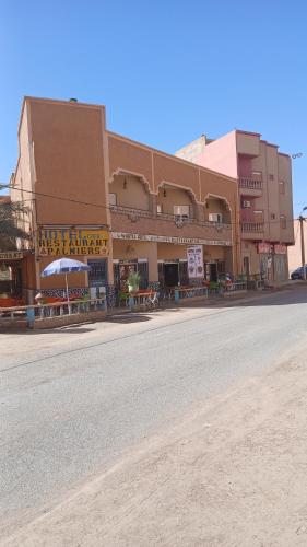 a large building with benches on the side of a street at Hôtel restaurant Palmiers in Alnif