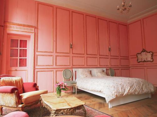 a bedroom with pink walls and a bed and chairs at Maison Pistache in Le Dorat