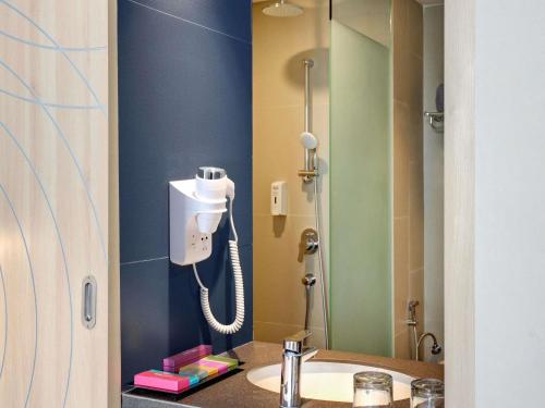 a bathroom with a phone on the wall next to a sink at ibis Styles Bogor Pajajaran in Bogor