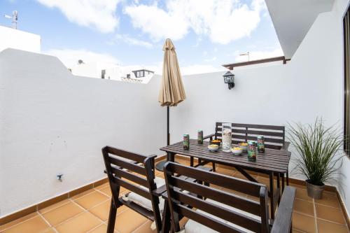 eine Terrasse mit 2 Stühlen, einem Tisch und einem Sonnenschirm in der Unterkunft Apartamento Remo in Playa Honda