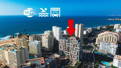 a city with a red arrow pointing to the ocean at Elite 3F Portimão com mar, piscina e garagem in Portimão