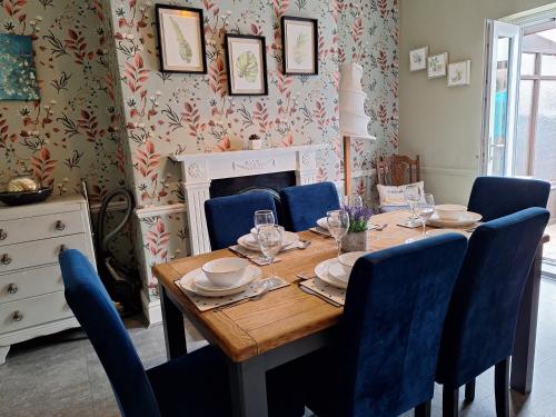 ein Esszimmer mit einem Holztisch und blauen Stühlen in der Unterkunft The Hampton Beautiful 3 Bedroom House with Conservatory & Garden in Scarborough