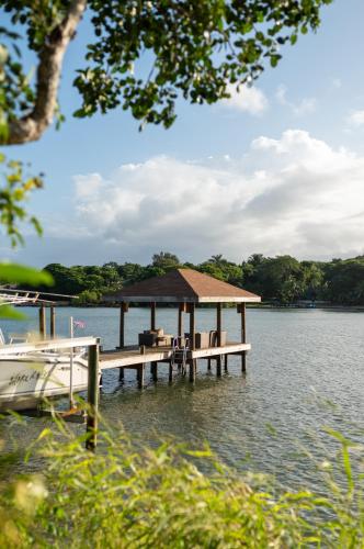 a dock with a pavilion on the water with a boat at Hotel Posada Las Orquídeas,West End in West End