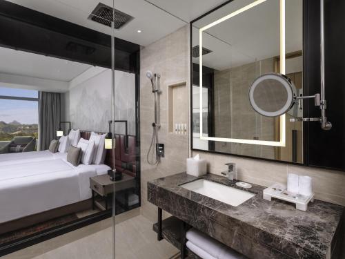 クラークにあるSwissôtel Clark Philippinesのベッドと洗面台と鏡のあるバスルーム